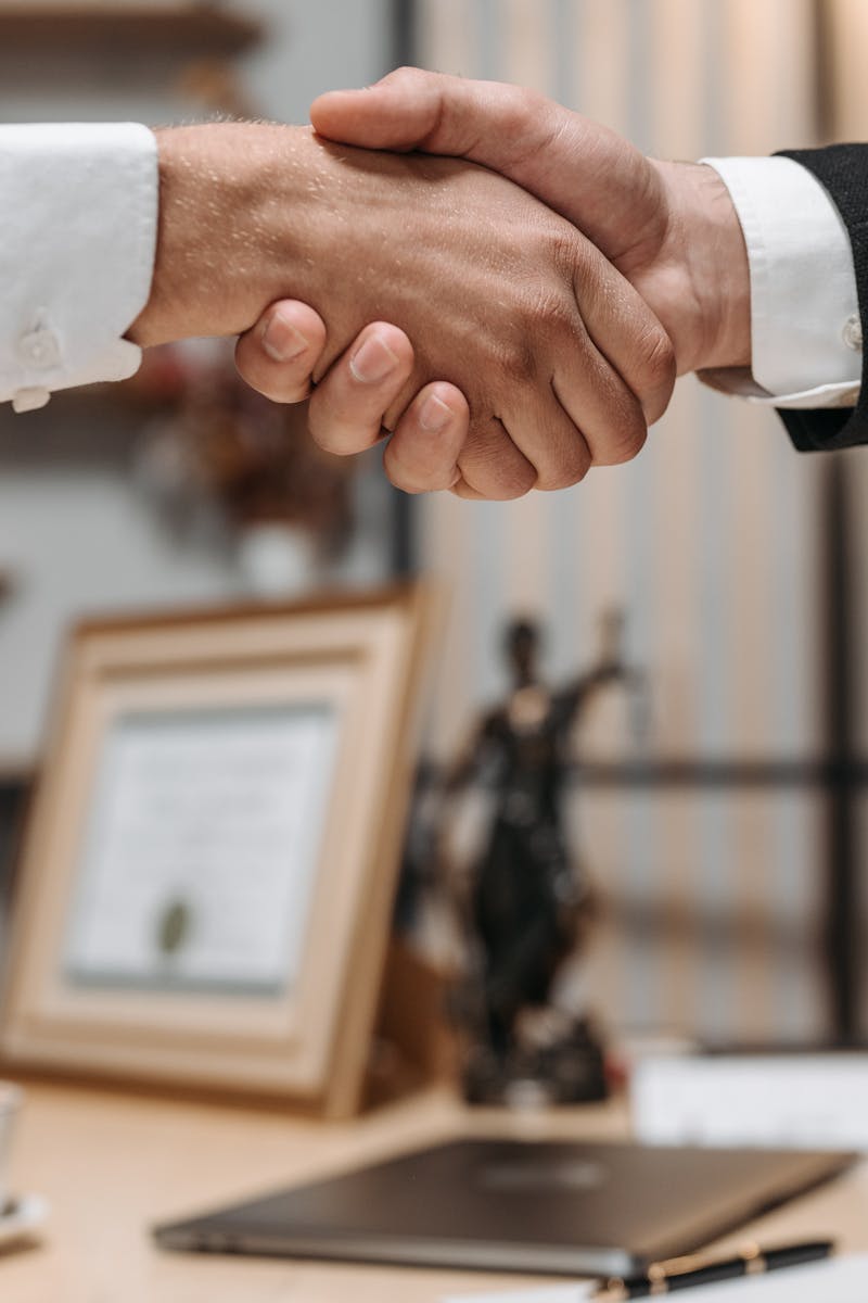 Close-up of a handshake between two professionals in a modern office setting, emphasizing partnership and agreement.